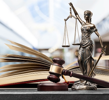 Justice et Droit : Statue, Marteau de Juge et Livre de Loi Statue de la justice avec balance et glaive, marteau de juge sur un livre de loi ouvert dans un tribunal.